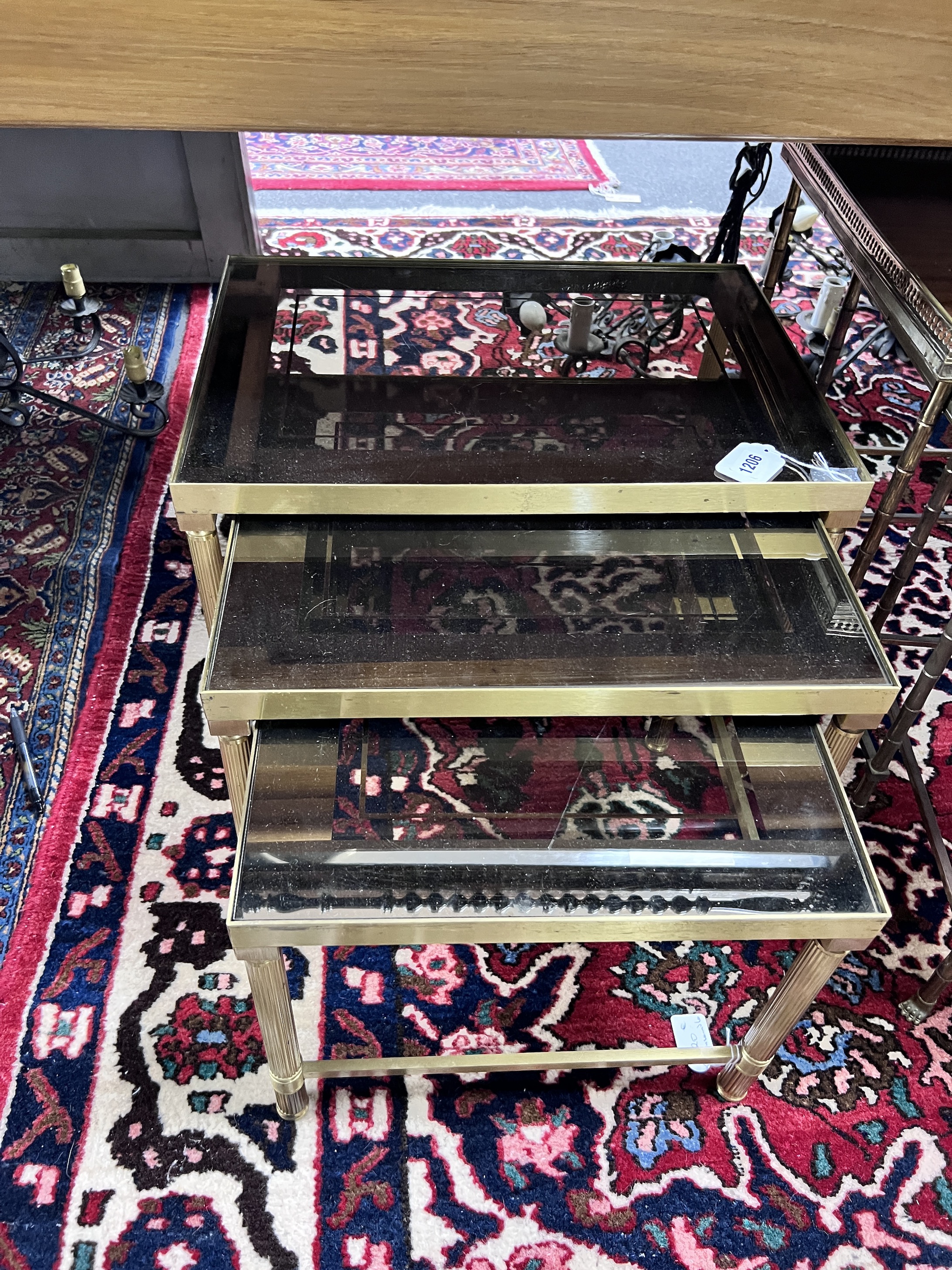 A nest of three 'Maison Charles' style brass and smoked glass topped tables, largest width 50cm